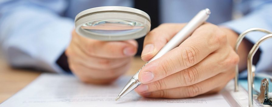 businessman is analyzing  through  magnifying glass contract and